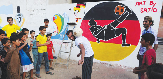 A Pakistani football fan demonstrates his skills in front of a mural celebrating the World Cup painted on the wall of a house in Karachi. (AFP) 