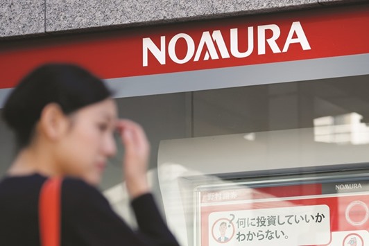 A woman stands outside a Nomura Securities Co branch, a unit of Nomura Holdings, in Tokyo. The biggest brokerage in Japan has about 2,500 employees in the Americas, most of whom work in the US and Canada.