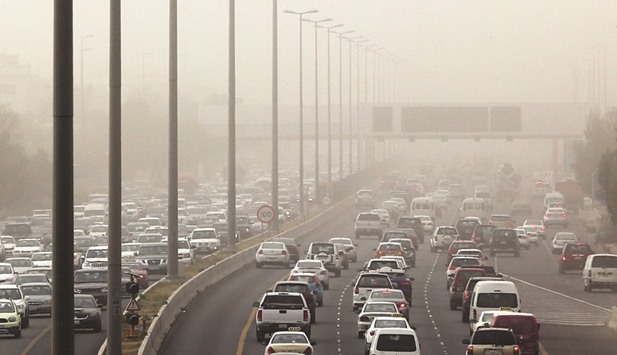 Vehicles drive during a heavy dust storm in Kuwait City yesterday as strong winds and dust caused low visibility on the main roads around the capital.