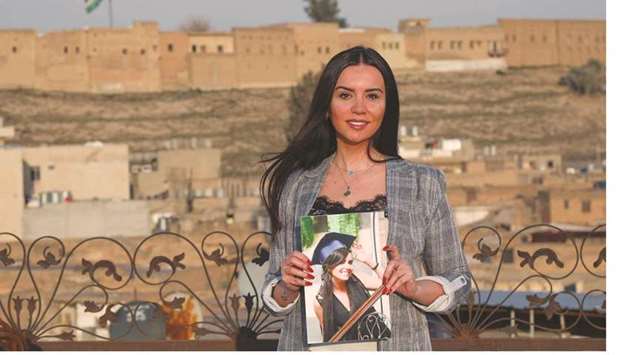 Dima al-Kaed, a 29-year-old Syrian journalist and refugee, poses for a picture in Arbil, the capital of Iraqu2019s northern autonomous Kurdish region, while holding in her hand a photo of herself dating from 2013 as a media graduate from Damascus University. (AFP)