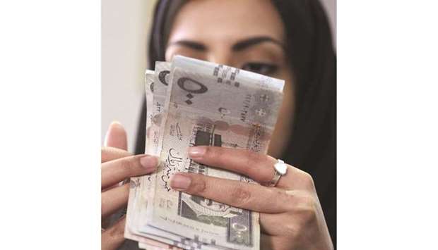 A woman counts Saudi riyal banknotes at a money exchange shop in Riyadh (file). Saudi Arabiau2019s inflation rate fell slightly to 5.2% in February from 5.7% in the prior month, the lowest since the kingdom tripled VAT in July to 15% to boost state revenues hurt by lower oil prices and the coronavirus crisis.