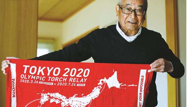 Masao Hashimoto who is going to run as a torch bearer on the first day of the torch relay at the Tokyo 2020 Olympic Games shows a towel promoting the torch relay during an interview with Reuters in Iwaki, Fukushima prefecture, Japan, yesterday. (Reuters)