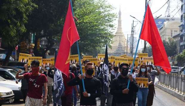 Protesters carrying flags of the National League for Democracy (NLD) party, during a demonstration against the military coup next to Sule pagoda in Yangon. FACEBOOK / AFP