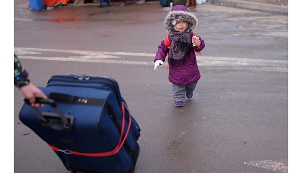 Angelina Rudnik, 2, walks behind her mother (not pictured) and luggage next to a shelter, before fleeing from Ukraine to Moldova following Russia's invasion, at the border crossing in Starokozache, Ukraine on March 11.  REUTERS/Nacho Doce