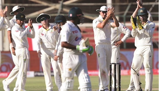 Australiau2019s players clap as Pakistanu2019s captain Babar Azam walks back to the pavillon after his dismissal during the fifth and final day of the second Test at the National Cricket Stadium in Karachi yesterday. (AFP)