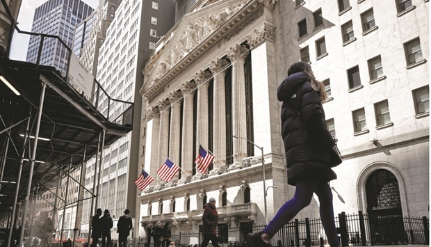 People are seen on Wall Street outside the New York Stock Exchange. Side-by-side declines in US equity and fixed income markets are pushing investors into cash, commodities and dividend-paying stocks as geopolitical uncertainty and worries over a hawkish Federal Reserve rock asset prices.