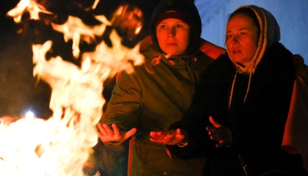 People fleeing the Russian invasion of Ukraine warm up by a fire barrel after crossing the border from Ukraine to Poland, at the border checkpoint in Medyka, Poland, March 6. REUTERS