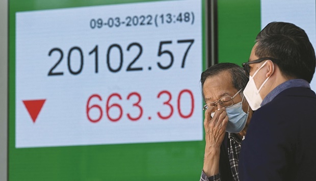 Two men chat in front of an electronic sign showing the market index in Hong Kong. The Hang Seng Index closed down 2.8% to 20,186.67 points yesterday.