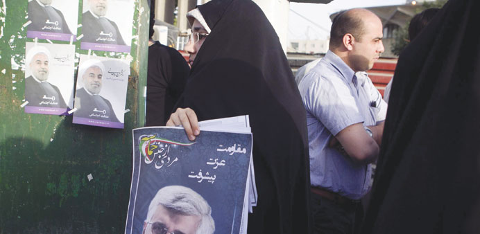 A supporter of Saeed Jalili holds his poster as she campaigns in Tehran on Thursday.