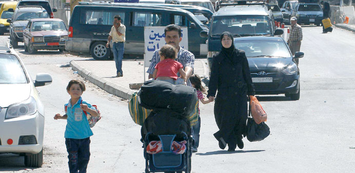 A Syrian family walks with their belongings after crossing the Masnaa border post between Syria and Lebanon yesterday in the Lebanese eastern Bekaa va