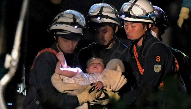 An eight-month-old baby is carried away by rescue workers after being rescued from her collapsed home caused by an earthquake in Mashiki town, Kumamoto prefecture, southern Japan.