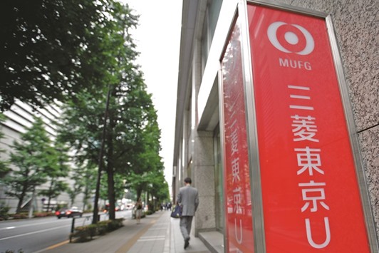 Signage for Bank of Tokyo Mitsubishi UFJ stands while a man exits a branch in Tokyo. Through its newly established Dubai branch, the bank has become the first  Japanese lender to provide Shariah-compliant corporate financing through an overseas branch after respective regulations have been loosened by Japanu2019s Financial Services Agency last year.