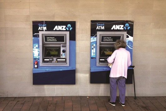 A customer uses an ANZ ATM at a branch in Sydney. The bank is considering selling its stake in Malaysian lender AMMB Holdings and Shanghai Rural Commercial Bank as it steps up efforts to exit minority stakes in Asia, people familiar with the matter said yesterday.