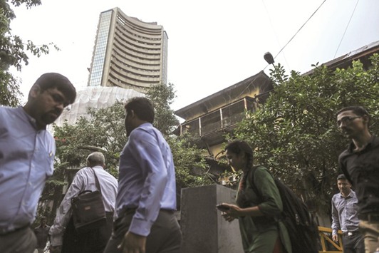 Pedestrians walk past the Bombay Stock Exchange which stands partially covered by scaffolding in Mumbai. The BSE Sensex closed higher by 190 points to 30,133 for the first time yesterday.