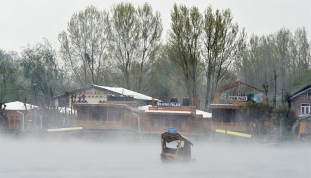 Kashmiri boatmen paddle a shikara across Dal Lake amid dense fog following rainfall in Srinagar on Thursday.