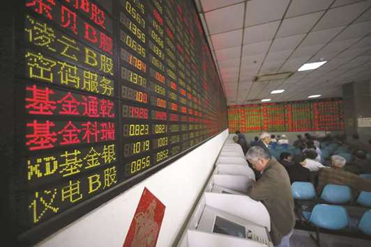 Investors look at computer screens showing stock information at a brokerage house in Shanghai. Chinau2019s large-cap CSI 300 Index advanced 0.5% yesterday, its first gain in five days, after the central bank cut reserve requirements for some lenders.