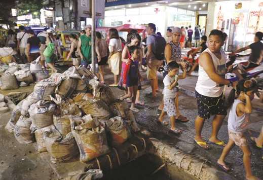 People walk past a clogged sewer and uncollected sacks containing waste from the sewers along a road at Boracay.