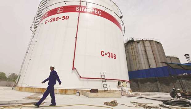 An employee walks past oil tanks at a Sinopec refinery in Wuhan, Hubei province. Sinopec, Asiau2019s largest crude oil buyer and its largest refiner, in January abandoned a buying formula used since 2014 to establish performance targets for Unipec and aimed at driving down its crude feedstock costs to a pre-set discount to global oil benchmarks.