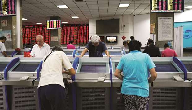 Investors look at computer screens showing stock information at a  brokerage house in Shanghai (file). Analysts tracked by Bloomberg predict Kweichow Moutai Co will be featuring the equity marketu2019s first 1,000 yuan stock within the next 12 months.
