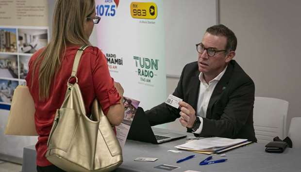 A representative hands a business card to a job seeker during a job fair in Miami. Initial claims for state unemployment benefits dropped 810,000 to a seasonally adjusted 4.427mn for the week ended April 18, the government said.