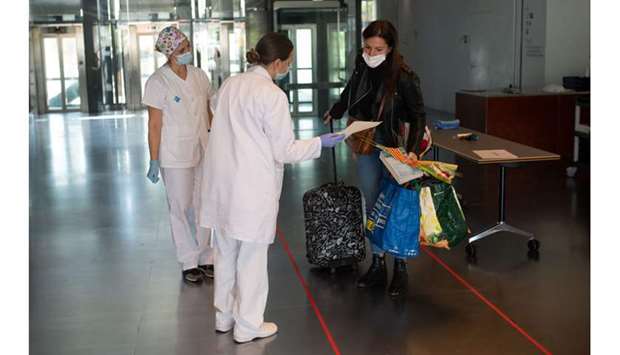 Healthcare workers offer a book and a rose to a cured coronavirus patient as she is discharged from the field hospital of Hotel Catalonia Fira in Barcelona yesterday, during the Sant Jordi festivities marking Saint Georgeu2019s Day. Traditionally men give women roses and women give men a book to celebrate the Catalan holiday, also known as u2018The Day of the Roseu2019 or u2018The Day of the Booku2019.