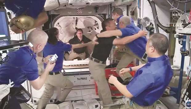 This screen grab taken from the Nasa live feed shows crew members of the International Space Station (ISS) welcoming crew of the SpaceXu2019s Crew Dragon spacecraft.