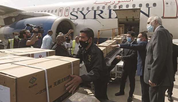 Syrian Health Minister Hassan al-Ghabash (third right), Syrian Deputy Foreign Minister Bashar al-Jaafari (right) and the Chinese ambassador Feng Biao (second right) oversee the unloading of aid boxes containing the Sinopharm Covid-19 vaccine, donated by China, at the Damascus International Airport, yesterday.
