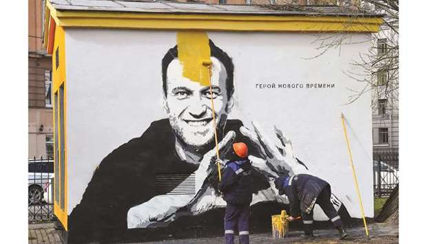 A worker paints over graffiti of Navalny in Saint Petersburg. The inscription reads u2018The hero of the new timesu2019.