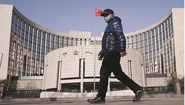 A man wearing a mask walks past the headquarters of the Peopleu2019s Bank of China in Beijing (file). Heightened global risks from the war in Ukraine and within China widespread Covid-19 lockdowns and a weak property market have triggered convulsions in the worldu2019s second-largest economy that are quickly spilling over into global supply chains.