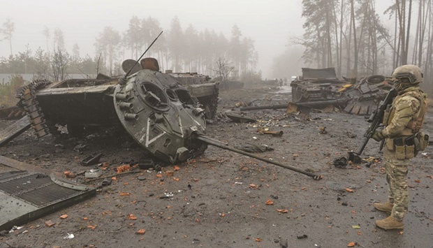 A Ukrainian service member stands next to destroyed Russian military vehicles, as Russiau2019s attack on Ukraine continues, in the village of Dmytrivka in Kyiv region, Ukraine, yesterday.