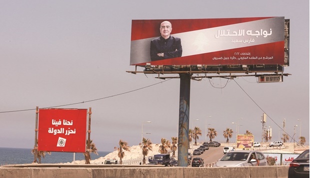 Cars pass near an electoral campaign sign that reads u201cWe face an occupationu201d, ahead of the parliamentary election that is scheduled for May 15, in Dbayeh.