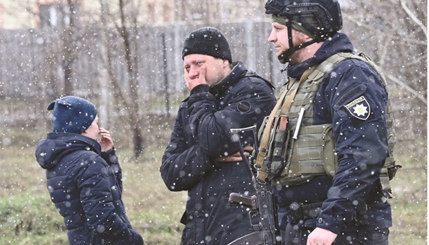 People react as they gather close to a mass grave in the town of Bucha, just northwest of the Ukrainian capital Kyiv, yesterday. (AFP)