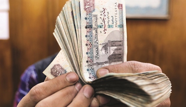 An employee counts Egyptian pounds at a foreign exchange office in central Cairo (file). Gulf Arab countries are channelling up to $22bn to Egypt to help it overcome a currency crisis, the third such rescue in a decade, as analysts watch for greater exchange rate flexibility to avert future crises.