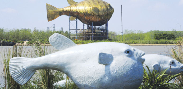 A viewing tower in the shape of a giant copper puffer fish is seen behind a sculpture of puffer fish (front) in Yangzhong county, Jiangsu province, Ch