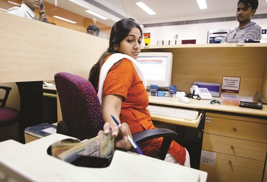 A cashier at the ICICI bank branch in New Delhi places rupee notes in a counting machine. The rupee closed at 66.88 yesterday, a level last seen on March 16, down 0.10% from its previous close of 66.81.