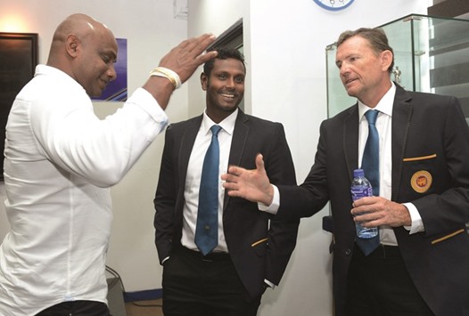 Sri Lanka coach Graham Ford (R) shakes hands with former skipper Sanath Jayasuriya (L) as captain Angelo Mathews looks on.