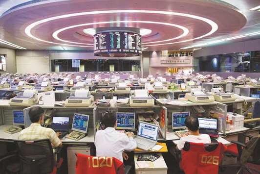 Stock traders sit at their desks facing an electronic board on the trading floor of the Hong Kong Stock Exchange. The Hang Seng fell 0.4% to 30,942.15 points yesterday.