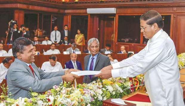 Sri Lanka President Maithripala Sirisena, right, swears in former justice minister Wijeyadasa Rajapakshe, left, into cabinet with the higher education and culture portfolios, during a ceremony in Colombo yesterday.
