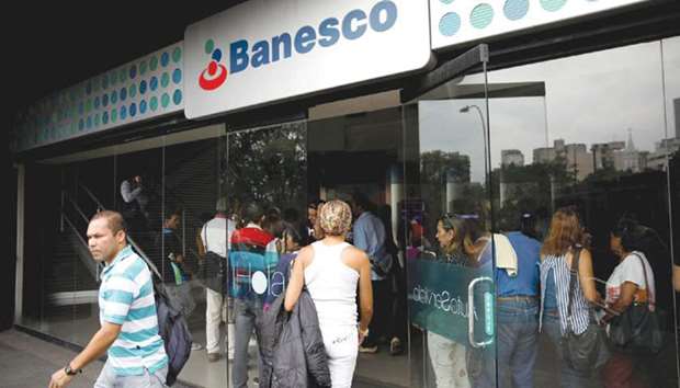 A man walks out from a Banesco bank branch in Caracas, Venezuela on Friday. The government claimed on Thursday the bank speculated on the exchange rate and smuggled paper money out of the country, freezing about 1,000 accounts. The banku2019s billionaire director, Juan Carlos Escotet, said the government knows about the accounts only because they were properly reported.