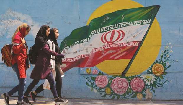 Young girls walk in front of a mural showing the Iranian national flag in the centre of the  capital Tehran (file). US President Donald Trump and Iranu2019s Supreme Leader Ayatollah Ali Khamenei both say that war is not on the horizon. But with no immediate prospect of talks and lacking any obvious back channels of communication, the void is filled by a history of mutual enmity.