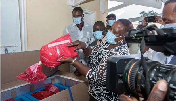 Malawiu2019s Health Minister Khumbize Kandodo Chiponda (C) lifts out a pack of expired Covid-19 Astra Zeneca from a transit box at an official ceremony at a pharmaceutical incinerator where the vaccines are to be destroyed at Kamuzu Central Hospital in Lilongwe