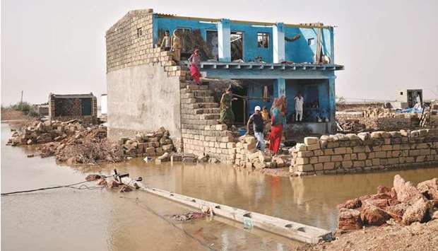 People stand beside a damaged house following cyclone Tauktae in Vadhera village in Gujarat, India.