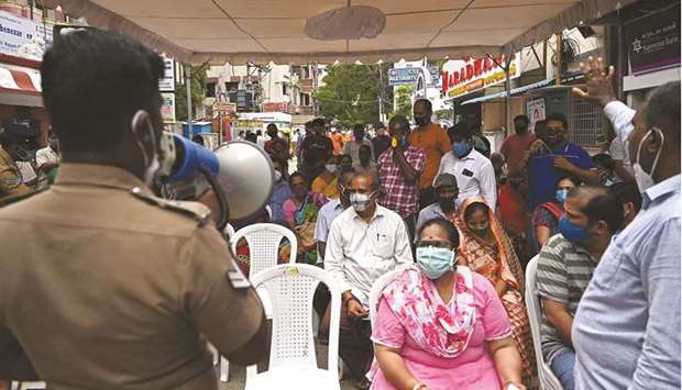 A security personnel makes announcement to people waiting to get themselves inoculated with the dose of Covishield vaccine at a vaccination camp in a residential area in Chennai yesterday.