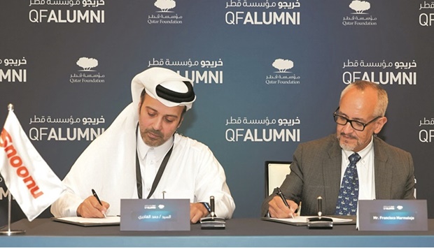 Hamad Mubarak al-Hajri (left) signing the MoU with a QF official.