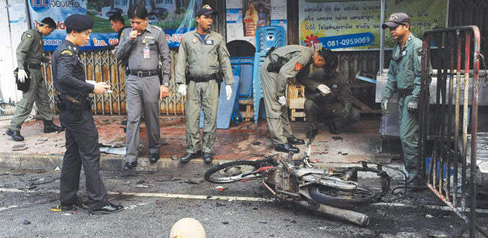 Members of a Thai bomb squad inspect the site of a motorcycle bomb blast triggered by suspected militants in front of a market in the restive southern