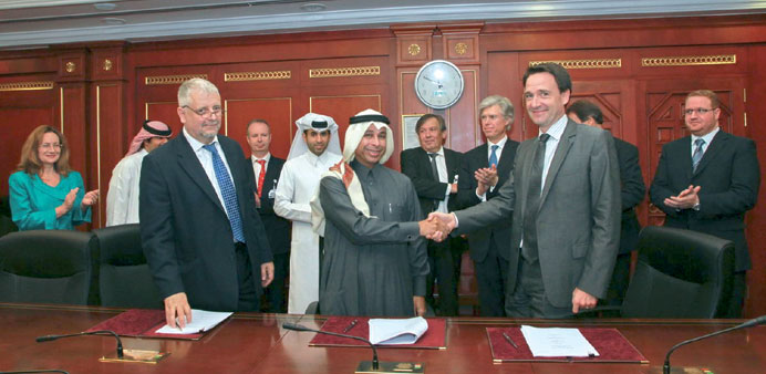 Al-Ghanim shakes hands with Michel as senior QP, Total and  Q Analytica executives look on.