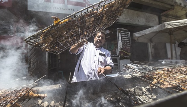 Egyptian cook Fathy grills chicken outside a restaurant in  Cairo.