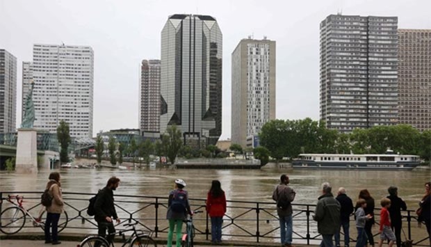 People look at the River Seine burst its banks in front of the Beaugrenelle quarter, next to the Statue of Liberty in Paris.