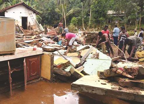 Residents clear debris from damaged homes following flooding in Yatagampitiya village in Bulathsinhala yesterday.