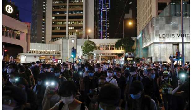 Pro-democracy demonstrators march holding their phones with flashlights on during a protest to mark the first anniversary of a mass rally against the now-withdrawn extradition bill, in Hong Kong yesterday.